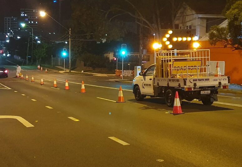 Roadwork truck with traffic cones at night.
