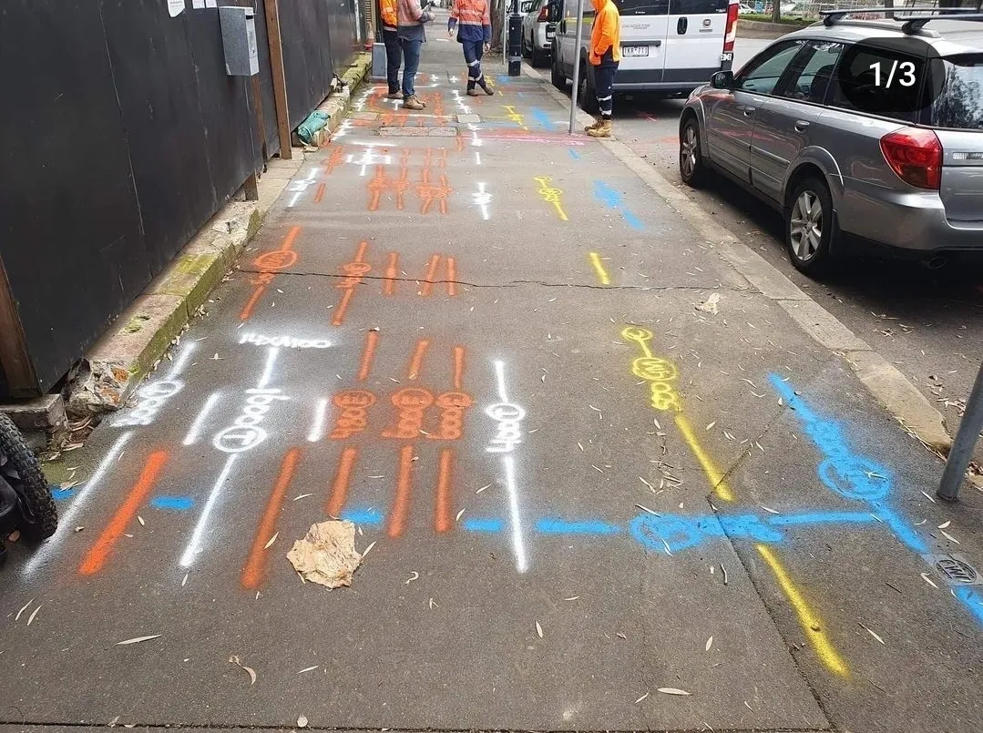 Colorful utility markings on urban sidewalk.