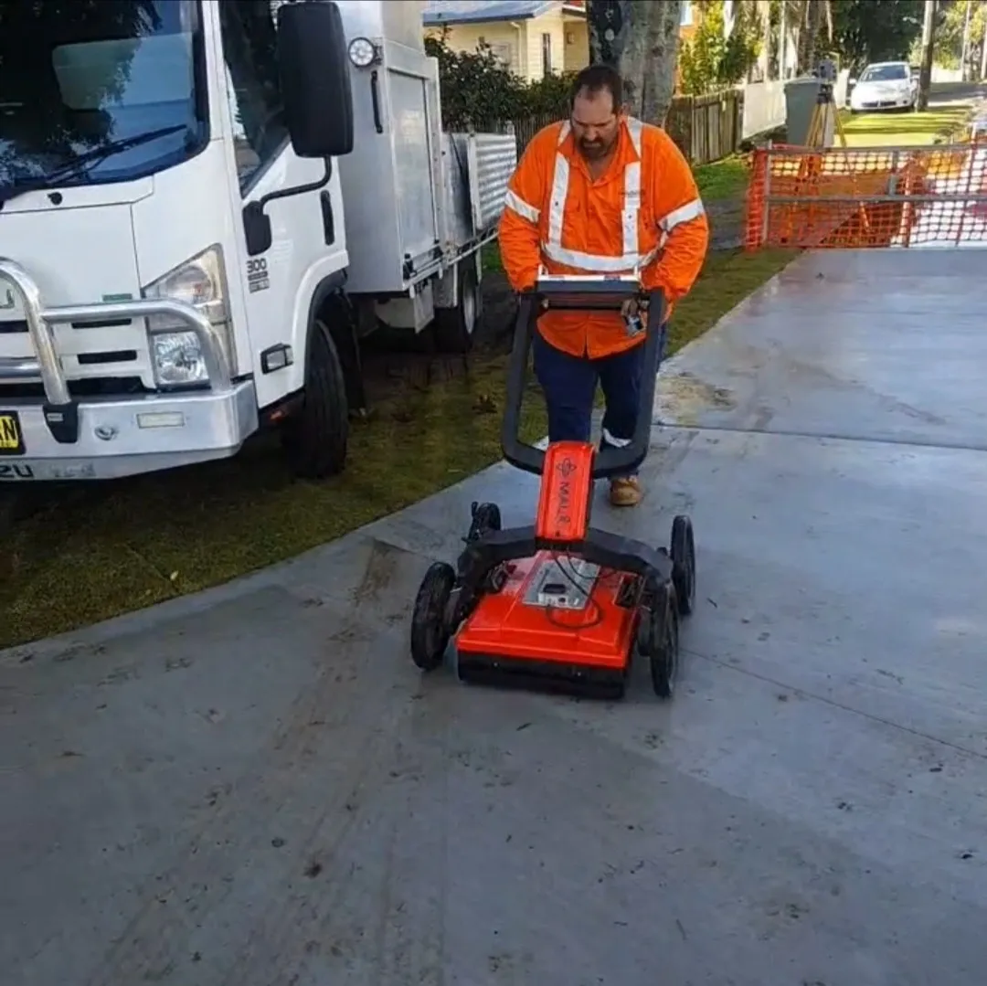 Worker using ground-penetrating radar on pavement.
