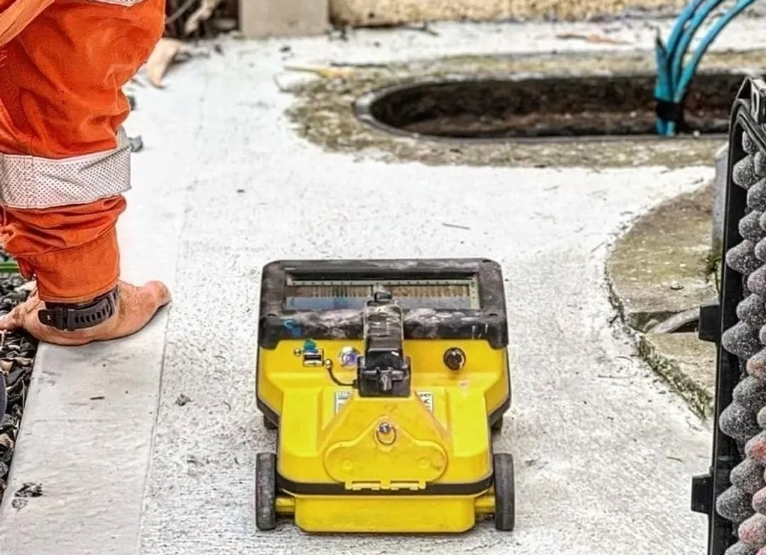 Worker with equipment near open manhole.
